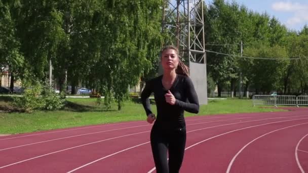 Schlanke, verschwitzte Frau läuft auf Sportplatz — Stockvideo