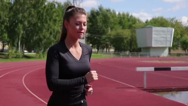 Mujer sudorosa delgada corriendo en el campo de atletismo — Vídeos de Stock