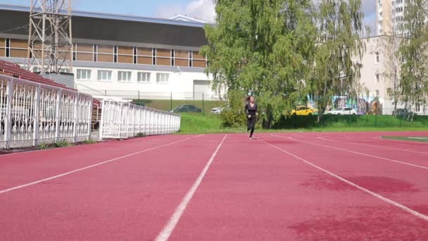 Λεπτή ιδρωμένη γυναίκα τρέχει σε αθλητικό πεδίο — Αρχείο Βίντεο