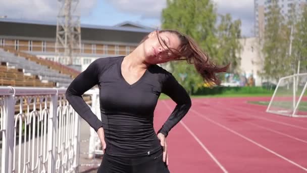 Zierliche schlanke Frau wärmt sich im Stadtstadion auf — Stockvideo