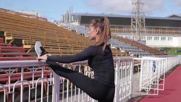 Graziosa donna magra riscaldandosi allo stadio della città — Video Stock