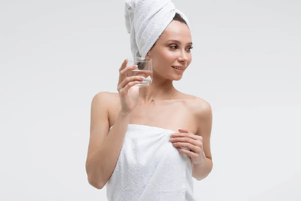 Confident relaxed woman with white towel on head drinking pure water and looking away — Stock Photo, Image