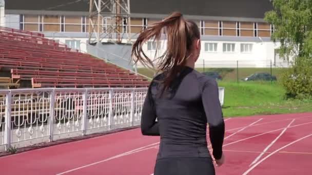 Vékony, lóversenypályán futó nő napsütésben — Stock videók
