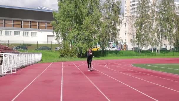 Λεπτή ιδρωμένη γυναίκα τρέχει σε αθλητικό πεδίο — Αρχείο Βίντεο
