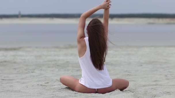 Mujer delgada sentada en posición de loto y alisando el cabello — Vídeo de stock