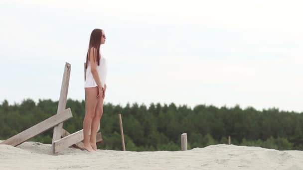 Сексуальная стройная женщина соблазнительно поднимает ноги на деревянной опоре — стоковое видео
