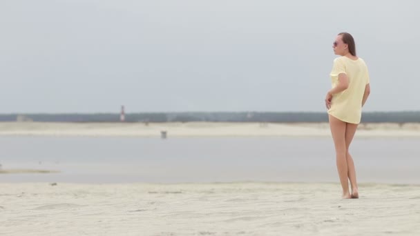 Sensual mujer caminando a lo largo de la playa de puntillas mostrando trajes de baño — Vídeos de Stock