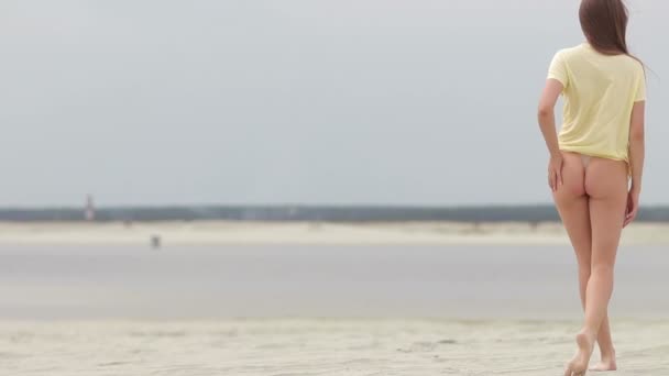 Sensual mujer caminando a lo largo de la playa de puntillas mostrando trajes de baño — Vídeo de stock