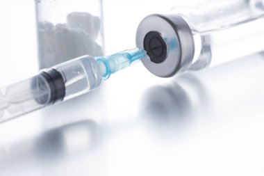 Beyaz arka planda plastik tek kullanımlık şırınga ile birlikte antibiyotik enjeksiyon şişeleri.