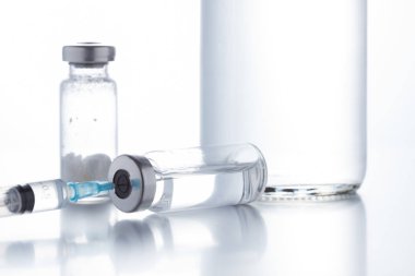 Beyaz arka planda plastik tek kullanımlık şırınga ile birlikte antibiyotik enjeksiyon şişeleri.
