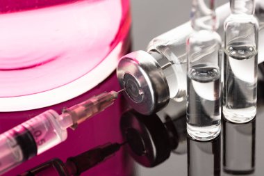 İğne için ampuller. Aşı için cam şişeler. Renkli arka planda şeffaf şişeler ve tek kullanımlık şırıngalar. Virüsü tedavi etmek için antibiyotik