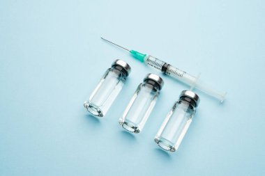 Bir sıra tıbbi ilaç şişesi. Şeffaf ilaç ve şırıngayla dolu cam şişeler..