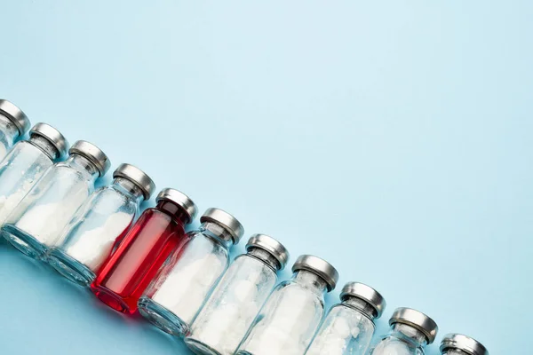 Bir sıra tıbbi ilaç şişesi. Enjeksiyon için toz ve açık arkaplanda kırmızı iksir olan cam şişeler.. — Stok fotoğraf