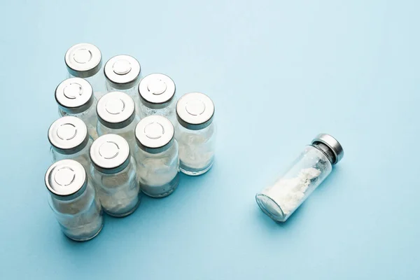 Una fila de viales médicos. Frascos de vidrio con polvo para inyección y vacunación sobre un fondo claro . —  Fotos de Stock