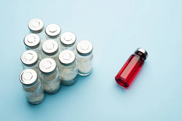 Una fila de viales médicos. Frascos de vidrio con polvo para inyección y uno con poción roja sobre fondo claro . —  Fotos de Stock