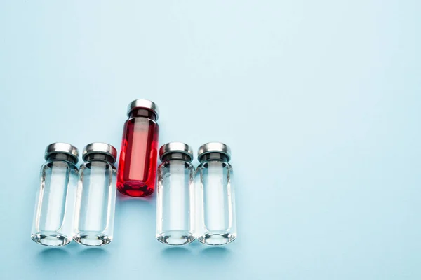 Rząd fiolek medycznych. Butelki szklane z przezroczystym lekiem i z czerwonym. — Zdjęcie stockowe