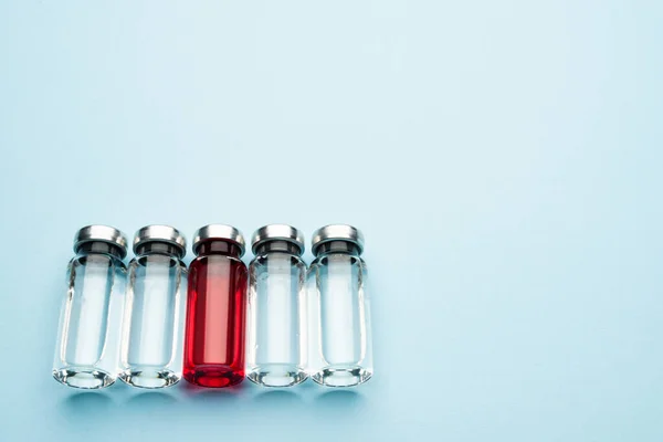 Bir sıra tıbbi ilaç şişesi. Şeffaf ilaçlı cam şişeler ve kırmızı şişeler.. — Stok fotoğraf