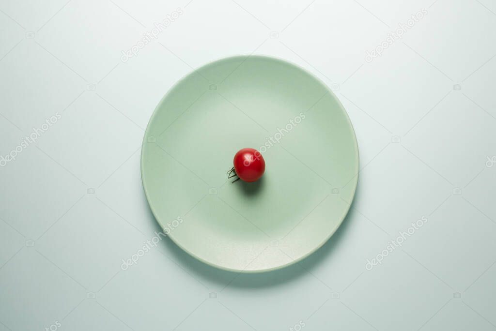 Turquoise plate with red tomato on a light background.
