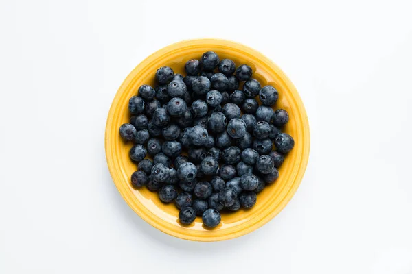 Голубые ягоды в желтой тарелке, вид сверху — стоковое фото