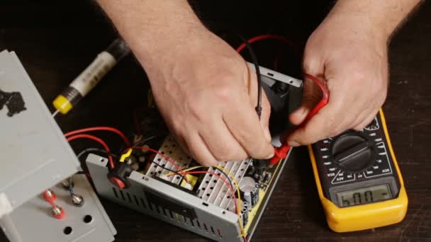 Electronist med en multimeter på en elektronisk produkt, från ovan — Stockvideo