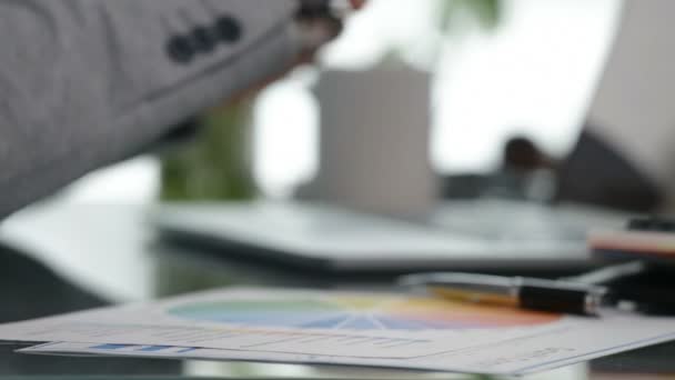 Close up of businessman working on laptop, checking graphs and taking notes, focus shift — Stock Video