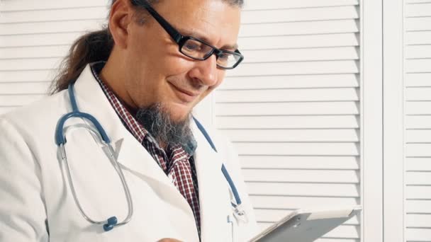 Веселый врач Холдинг цифрового планшета и проверка диагностики — стоковое видео