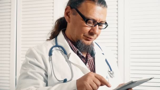 Cheerful physician holding a digital tablet and checking diagnostics — Stock Video