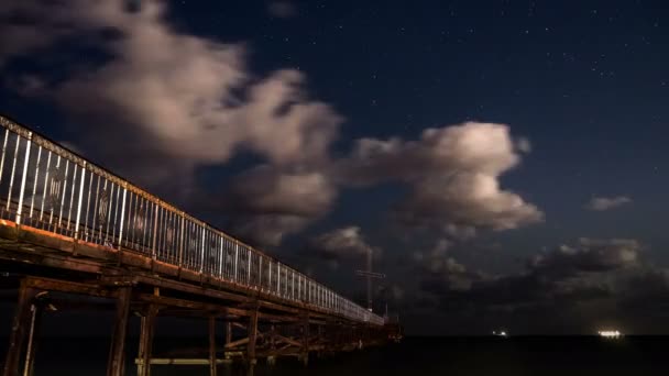 Stelle in movimento e nuvole sopra il molo. 4K time-lapse video di notte piena di stelle con nuvole sulla spiaggia in Bulgaria con onde marine . — Video Stock