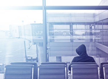 Kapüşonlu bir adam oturur