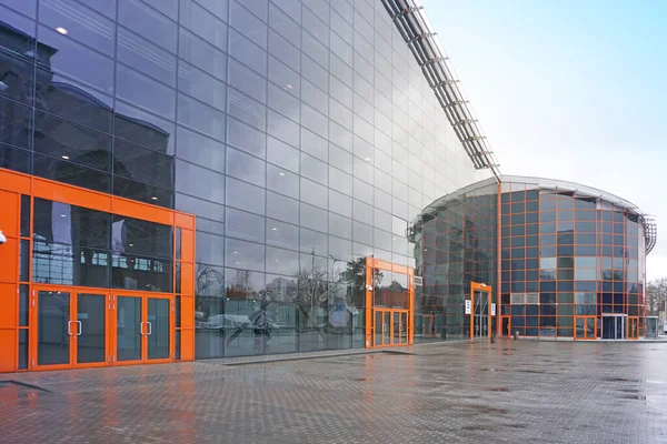Szklana Fasada Budynku Pomarańczowymi Drzwiami Która Odzwierciedla Inny Budynek — Zdjęcie stockowe