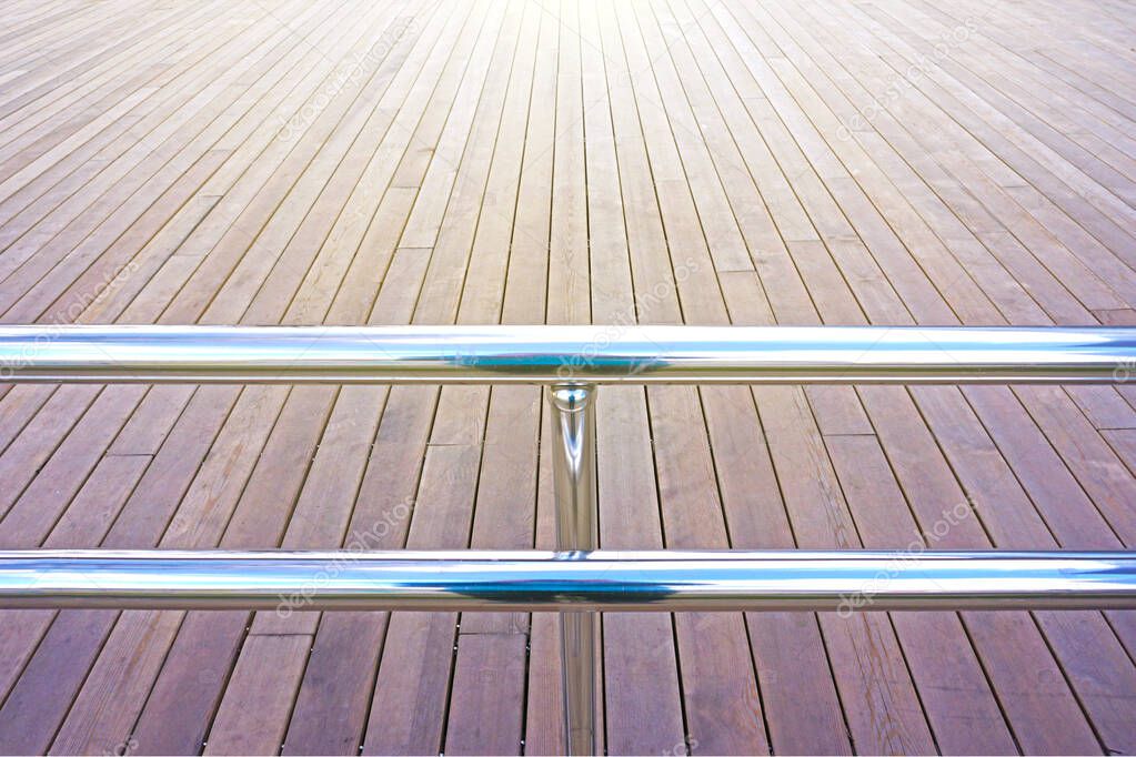 polished metal handrails on the background of a floor from boards                               