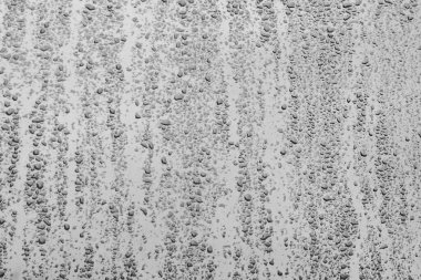 Mavi gökyüzü ve beyaz bulutlu bir pencereye su damlaları                               