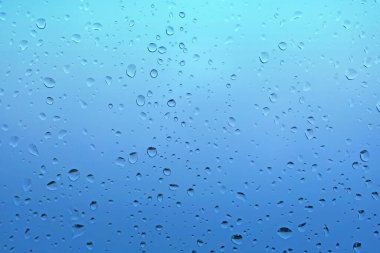 Pencere camına damlayan yağmur damlaları, mavi güzel arka plan. 