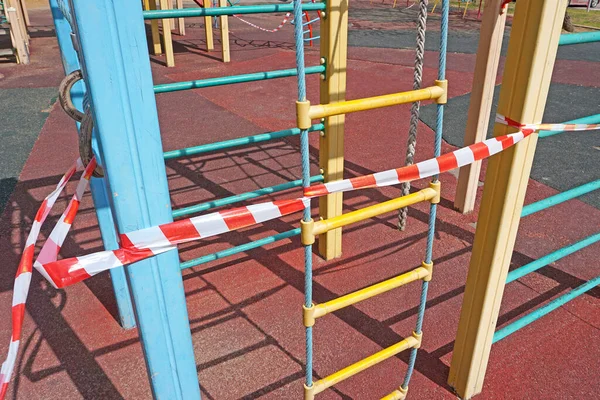 The playground is closed by a striped red and white tape fencing for quarantine during the coronavirus epidemic,COVID-1
