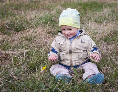 çimenlerin üzerinde parkta oturan küçük çocuk