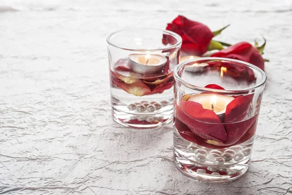 Día de San Valentín. Una vela y rosas rojas en vasos . —  Fotos de Stock