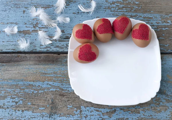 Ahşap arka plan üzerinde beyaz tabak içinde geleneksel Paskalya yumurtaları.