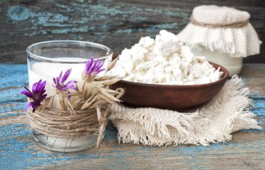 Süt ve peynir ahşap arka plan üzerinde bir kil plaka ile cam.