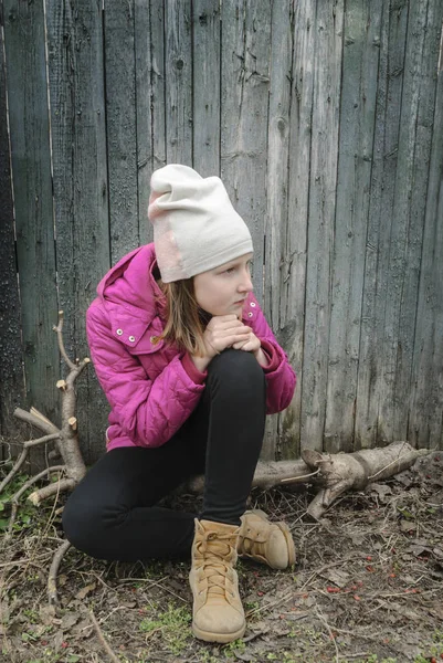 Teen girl sitting near the old fence — Stock Photo, Image