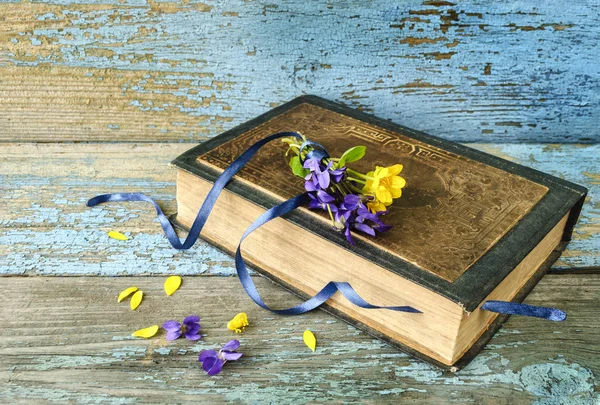 Vintage book and a small bouquet flowers on used old wooden surface. — Stock Photo, Image