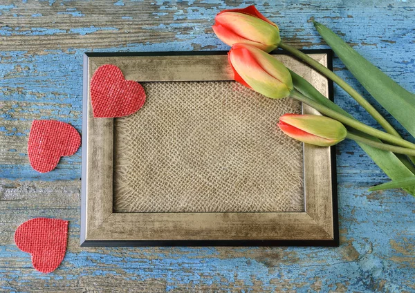Marco de fotos, tulipanes rojos y corazones sobre mesa de madera. Vista superior —  Fotos de Stock