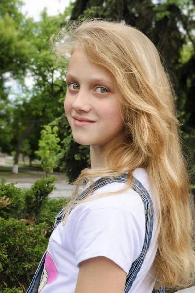 Szép mosolygó lány pózol zöld nyári háttér felett — Stock Fotó