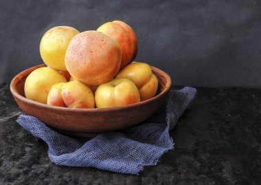 Karanlık bir arka plan üzerine bir tabak içinde olgun kayısı