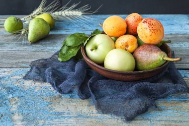 Elma, armut ve ahşap bir masa üzerinde bir tabak içinde kayısı