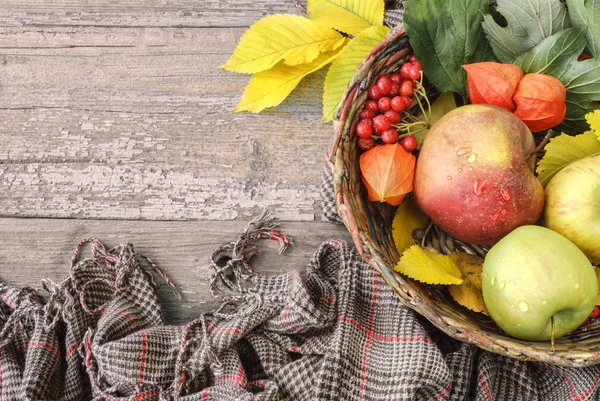 Olgun Kırmızı elma ve ahşap masa, boşaltmak yapraklarda ile hasır sepet, yakın çekim