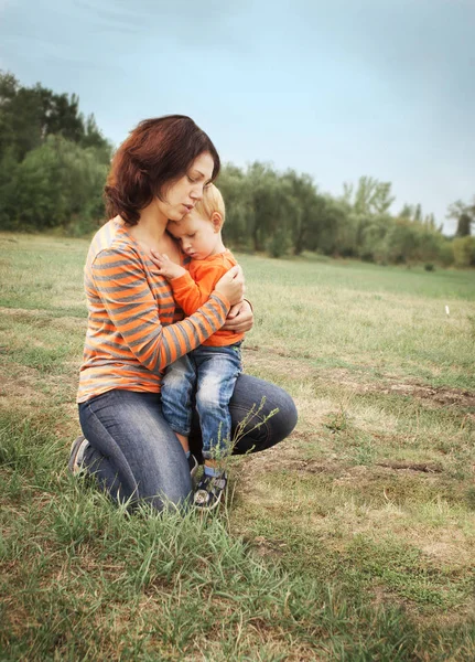 Mamma och hans lille son kramas på bakgrunden av en grön glade. — Stockfoto