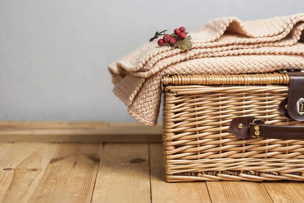 A picnic basket with knitted plaid on wood surface — Stock Photo, Image