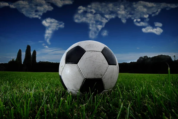 Fotboll boll på gräset med globe gjort av moln — Stockfoto