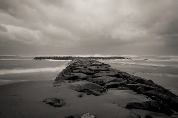 Falochron kamień na plaży. Ciemny burzliwy niebo i morze fale w Lazi — Zdjęcie stockowe