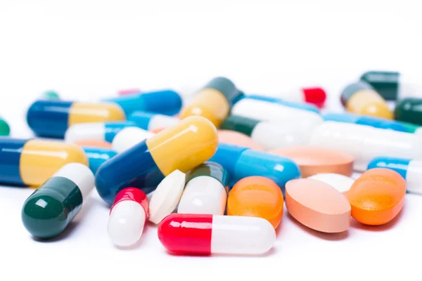 Цветные таблетки и капсулы на белом фоне — стоковое фото